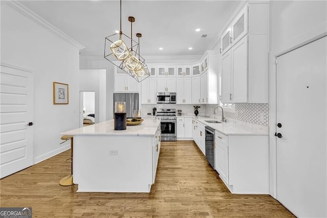 kitchen featuring ornamental molding, backsplash, white cabinets, stainless steel appliances, and light wood finished floors