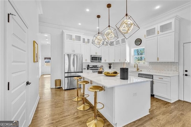 kitchen with crown molding, white cabinets, a breakfast bar, and stainless steel appliances