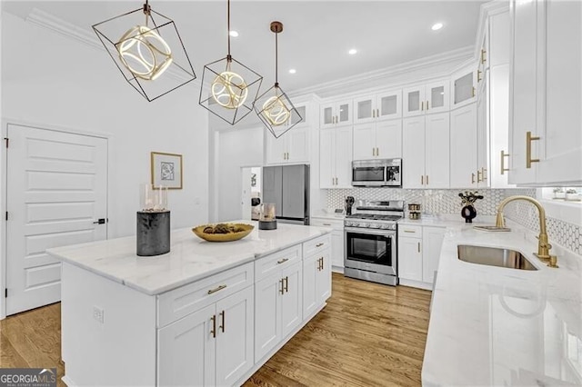 kitchen featuring a center island, light stone countertops, light wood-style floors, appliances with stainless steel finishes, and a sink