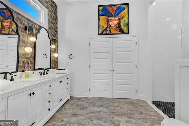 bathroom with a walk in shower, ornamental molding, wood finished floors, a sink, and double vanity