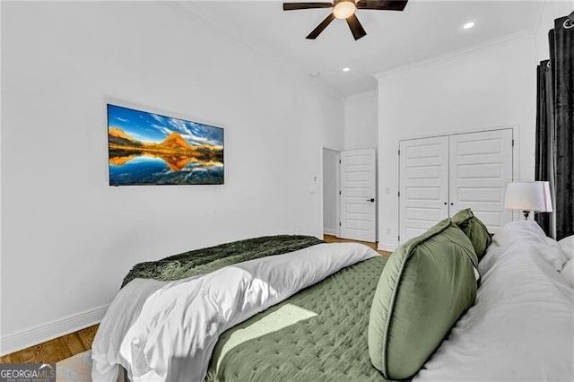bedroom with a closet, baseboards, recessed lighting, crown molding, and wood finished floors