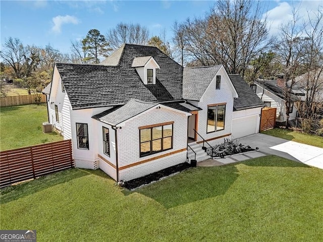 modern inspired farmhouse with a front yard, fence, brick siding, a shingled roof, and concrete driveway