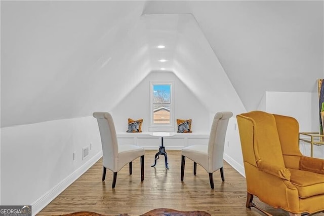 interior space featuring wood finished floors, visible vents, baseboards, and vaulted ceiling