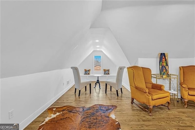 living area featuring baseboards, vaulted ceiling, and wood finished floors