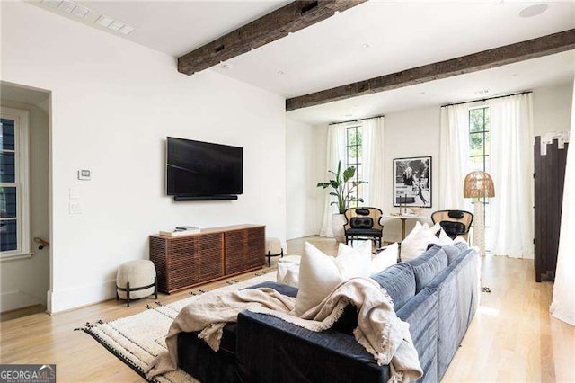 living area with light wood-style floors, beamed ceiling, and baseboards