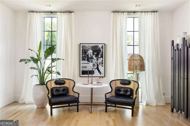 living area with wood finished floors, baseboards, and visible vents