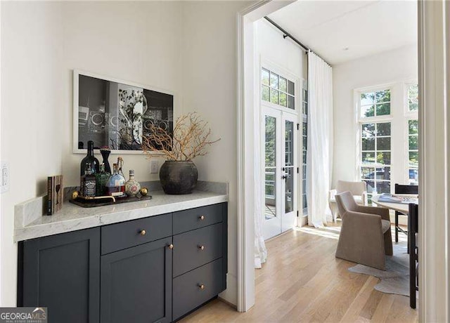 interior space featuring light wood-style floors, french doors, and a dry bar
