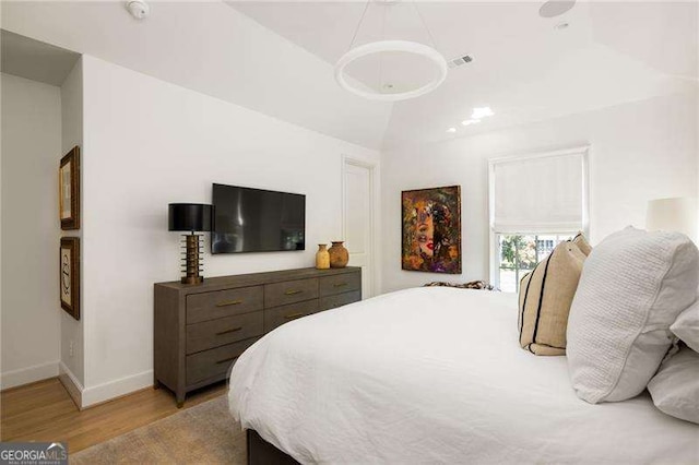 bedroom with light wood-style flooring, baseboards, and vaulted ceiling