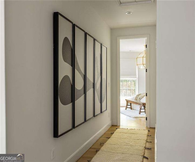 corridor featuring light wood-style flooring and baseboards