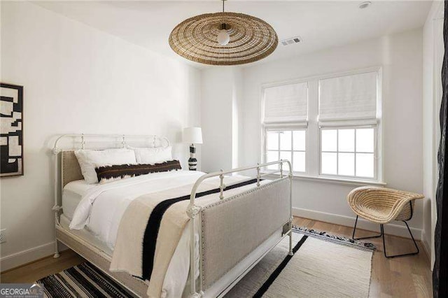 bedroom with visible vents, baseboards, and wood finished floors