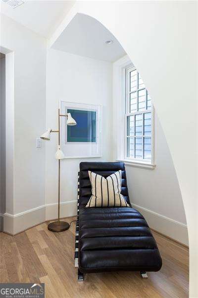 sitting room with arched walkways, wood finished floors, and baseboards