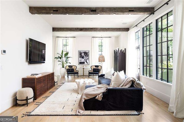 living room featuring light wood-style flooring, beamed ceiling, and baseboards