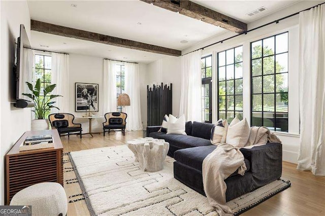 living area with wood finished floors, beamed ceiling, and visible vents