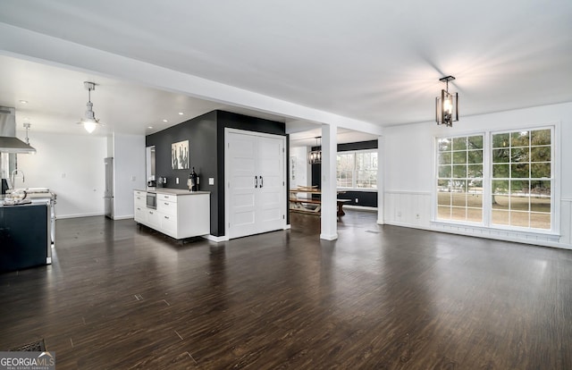 unfurnished living room with recessed lighting, dark wood finished floors, a wainscoted wall, and baseboards