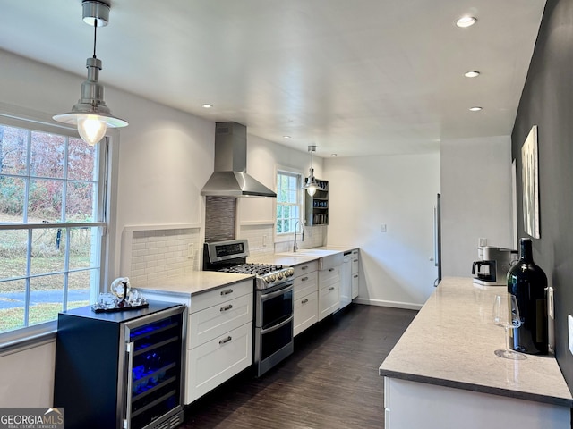 kitchen with a sink, double oven range, backsplash, wall chimney exhaust hood, and recessed lighting