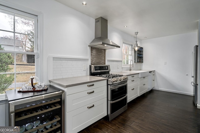 kitchen with island exhaust hood, tasteful backsplash, light countertops, beverage cooler, and appliances with stainless steel finishes