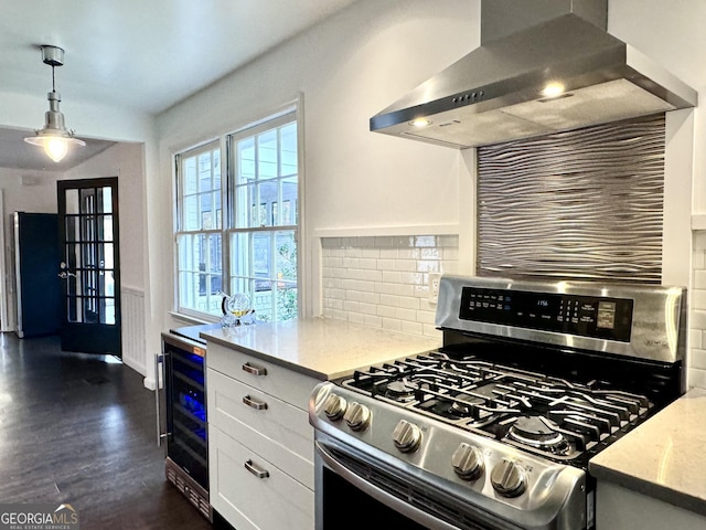 kitchen featuring wine cooler, tasteful backsplash, stainless steel gas range, white cabinetry, and wall chimney range hood