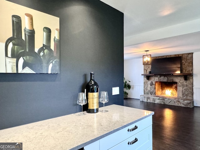 bar featuring a stone fireplace and dark wood-type flooring
