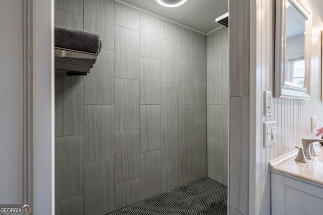 bathroom with a tile shower, crown molding, and vanity