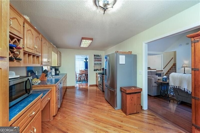209 Red Fern Ct, Canton, GA 30114 - kitchen featuring stainless steel appliances, light wood finished floors, a sink, and a textured ceiling