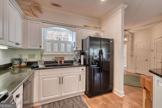 kitchen with black fridge, dishwasher, white cabinets, a sink, and light wood-style floors