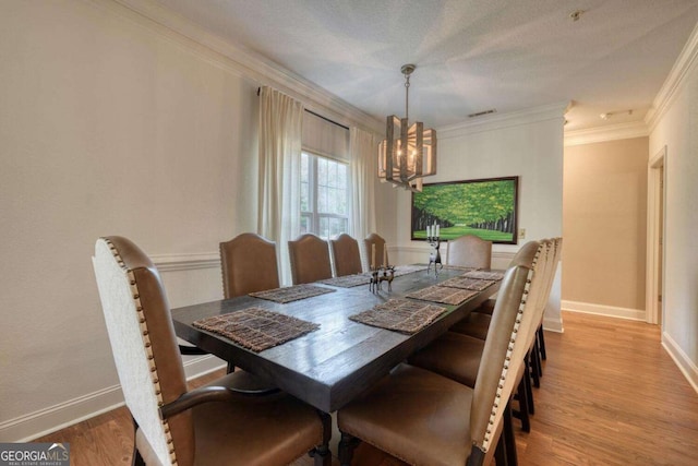 dining area featuring a chandelier, ornamental molding, wood finished floors, and baseboards