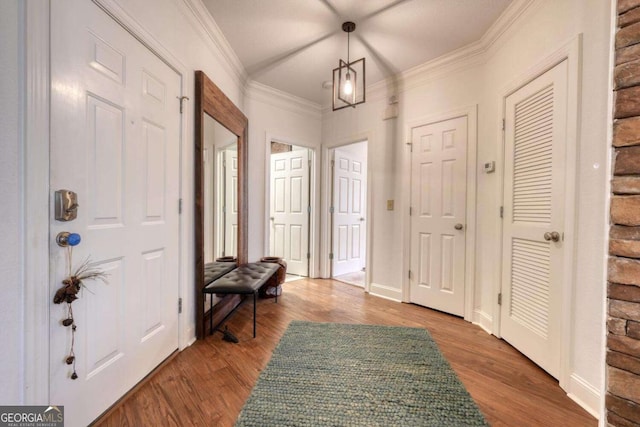 foyer entrance featuring wood finished floors, ornamental molding, and baseboards