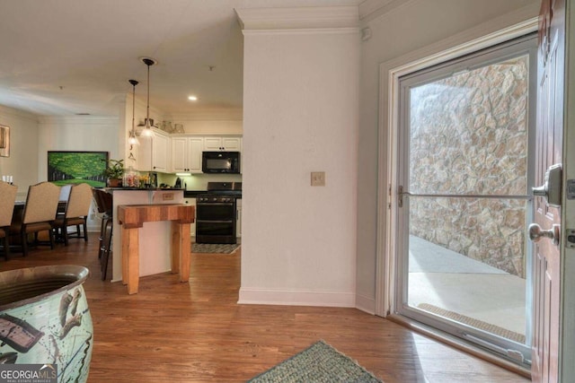 kitchen with range with two ovens, black microwave, crown molding, dark countertops, and wood finished floors