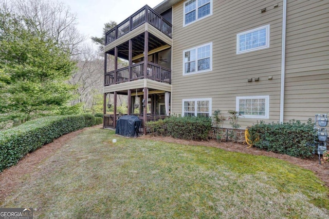 rear view of property featuring a balcony and a lawn
