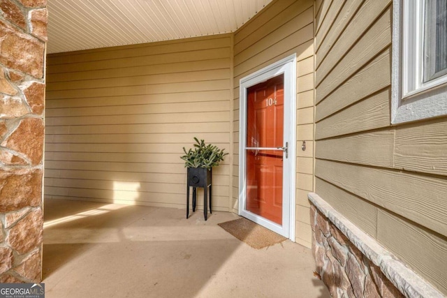 view of exterior entry with stone siding and a patio