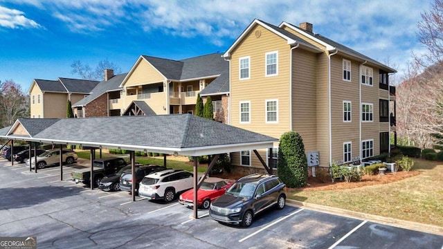 view of building exterior featuring covered and uncovered parking