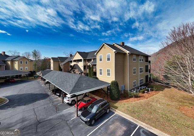 view of property with covered and uncovered parking and a residential view