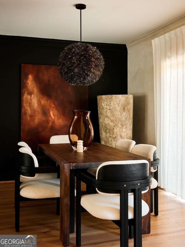 dining area with light wood-style flooring and crown molding
