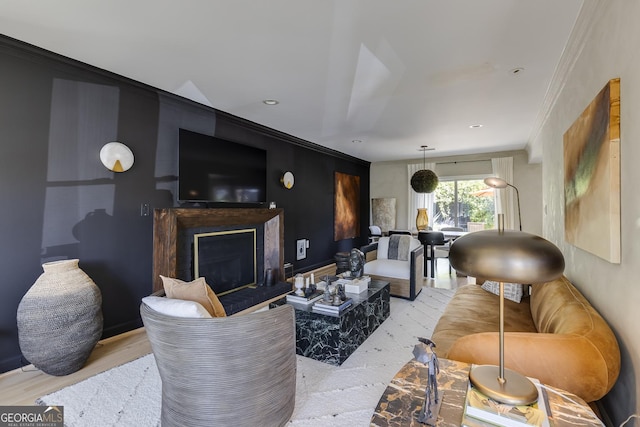 living area with a fireplace with raised hearth and crown molding