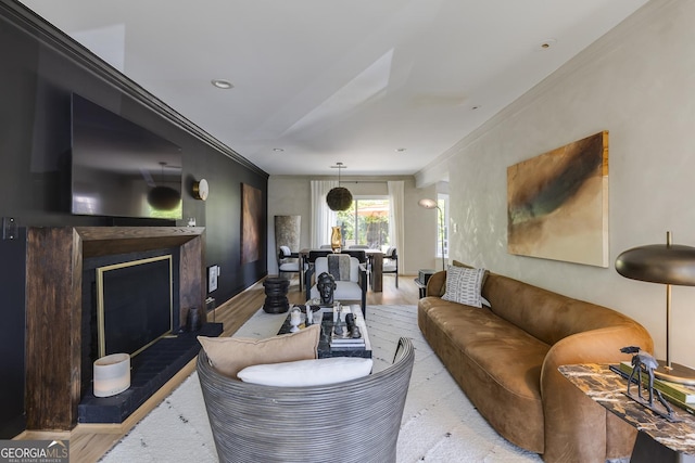 living area with crown molding, wood finished floors, baseboards, and a fireplace with raised hearth