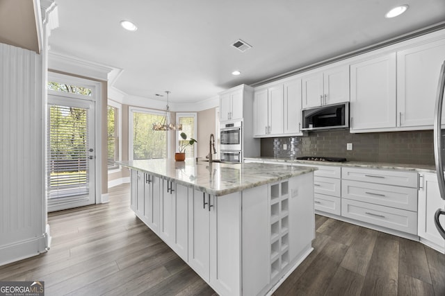 774 Mary Ann Dr NE, Marietta, GA 30068 - kitchen featuring an island with sink, white cabinetry, ornamental molding, visible vents, and appliances with stainless steel finishes