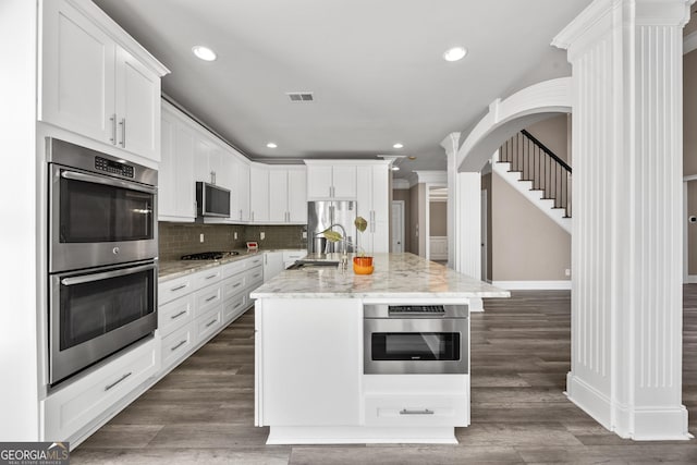 774 Mary Ann Dr NE, Marietta, GA 30068 - kitchen with dark wood-style floors, backsplash, white cabinets, visible vents, and stainless steel appliances