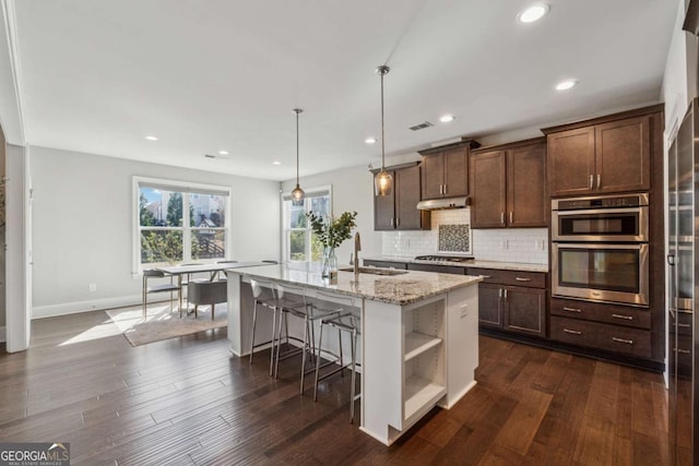 214 Leland Way, Woodstock, GA 30188 - kitchen with open shelves, under cabinet range hood, a sink, a center island with sink, and decorative backsplash