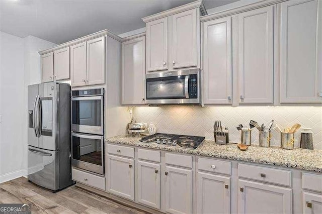75 Glen Abbey Cir, Fairburn, GA 30213 - kitchen with light stone countertops, light wood-style flooring, backsplash, and appliances with stainless steel finishes