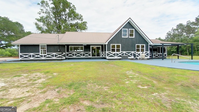 rear view of house with a lawn, metal roof, and an outdoor pool