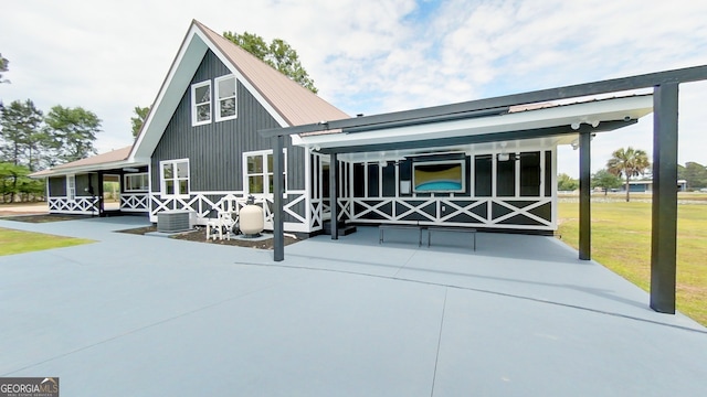 back of house featuring a patio area, a yard, metal roof, and central AC unit