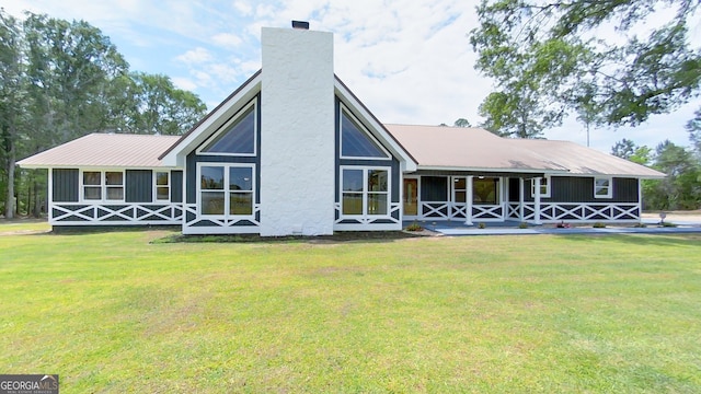 rear view of house with a yard, a porch, and metal roof