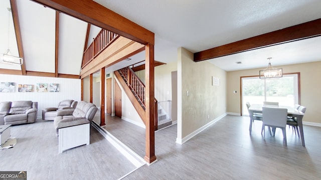 living area featuring wood finished floors, stairs, baseboards, beam ceiling, and a chandelier