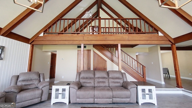 living area with high vaulted ceiling, concrete flooring, stairs, and beam ceiling