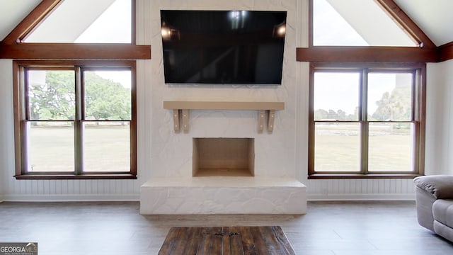 living area featuring lofted ceiling, baseboards, and wood finished floors