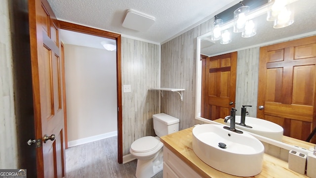 bathroom featuring toilet, a textured ceiling, wood finished floors, baseboards, and vanity