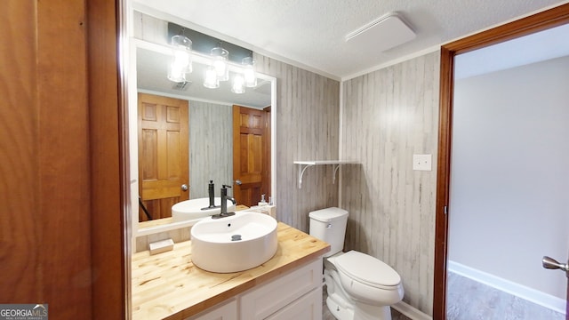 half bath with toilet, vanity, wood finished floors, and a textured ceiling