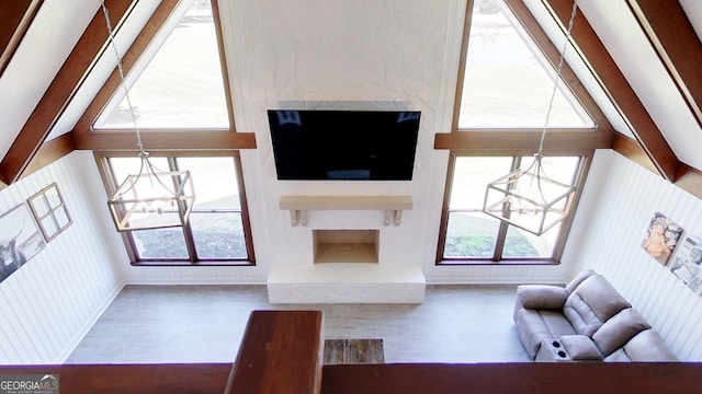 living area with a chandelier, wood finished floors, a premium fireplace, and baseboards