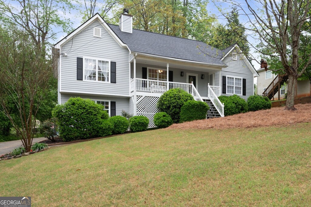 view of front of property featuring a porch, roof with shingles, a front lawn, stairs, and a chimney
