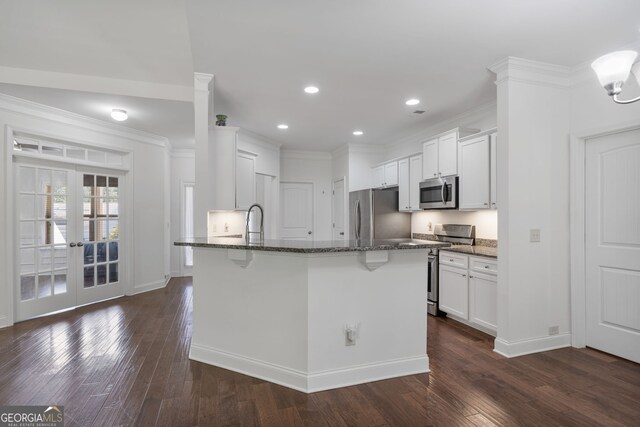 328 Spence Cir, Ball Ground, GA 30107 - kitchen featuring appliances with stainless steel finishes, dark stone counters, a kitchen bar, dark wood finished floors, and ornamental molding